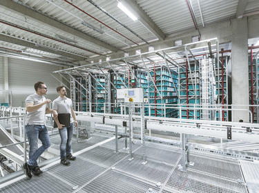 Two team members talk on top of a catwalk inside a logistics center Two team members talk on top of a catwalk inside a logistics center