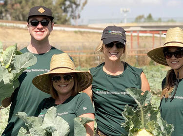 Prologis employees in a field holding cabbage 