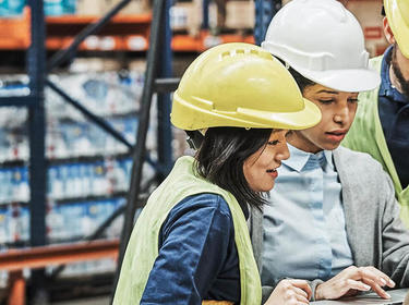 two women in a warehouse looking on a laptop