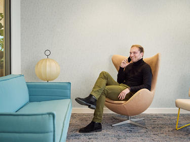 Man sitting in a chair calling on the phone