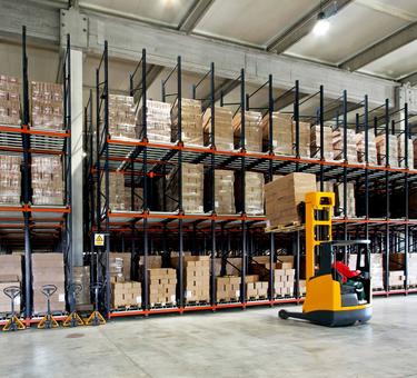 Forklift placing product on a rack in a warehouse