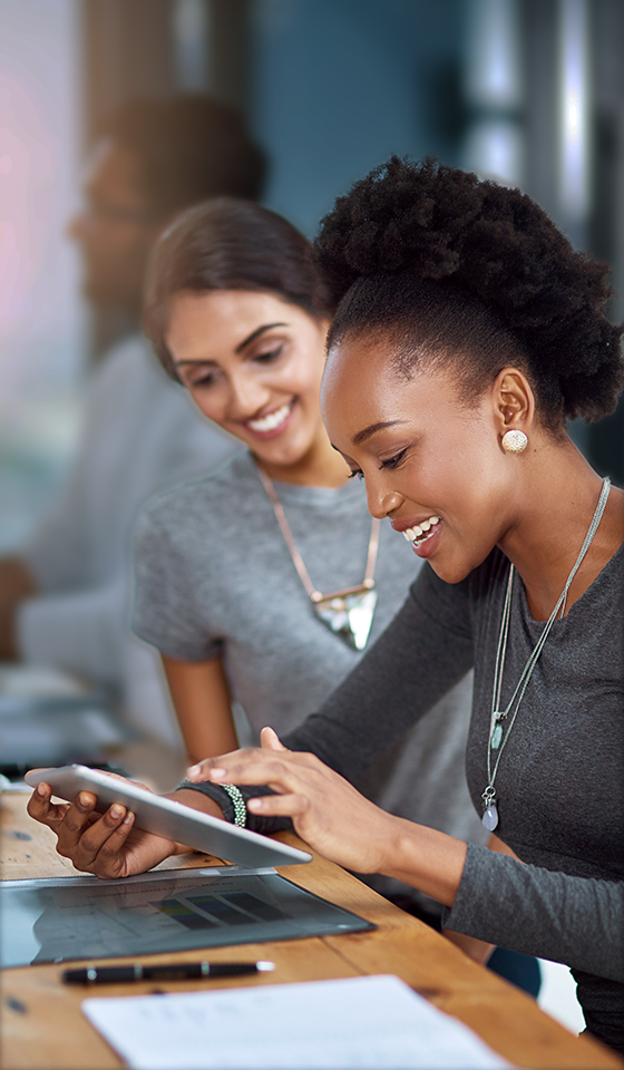 Twee vrouwen die glimlachen en naar een iPad kijken Twee vrouwen die glimlachen en naar een iPad kijken
