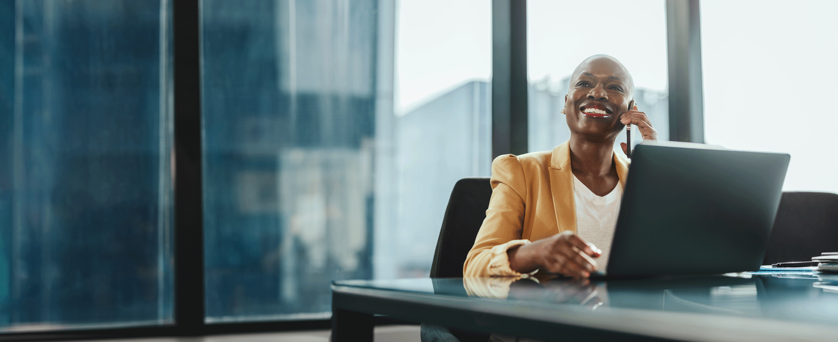 Vrouw die aan het werk is achter haar laptop en aan de telefoon in gesprek is Vrouw die aan het werk is achter haar laptop en aan de telefoon in gesprek is